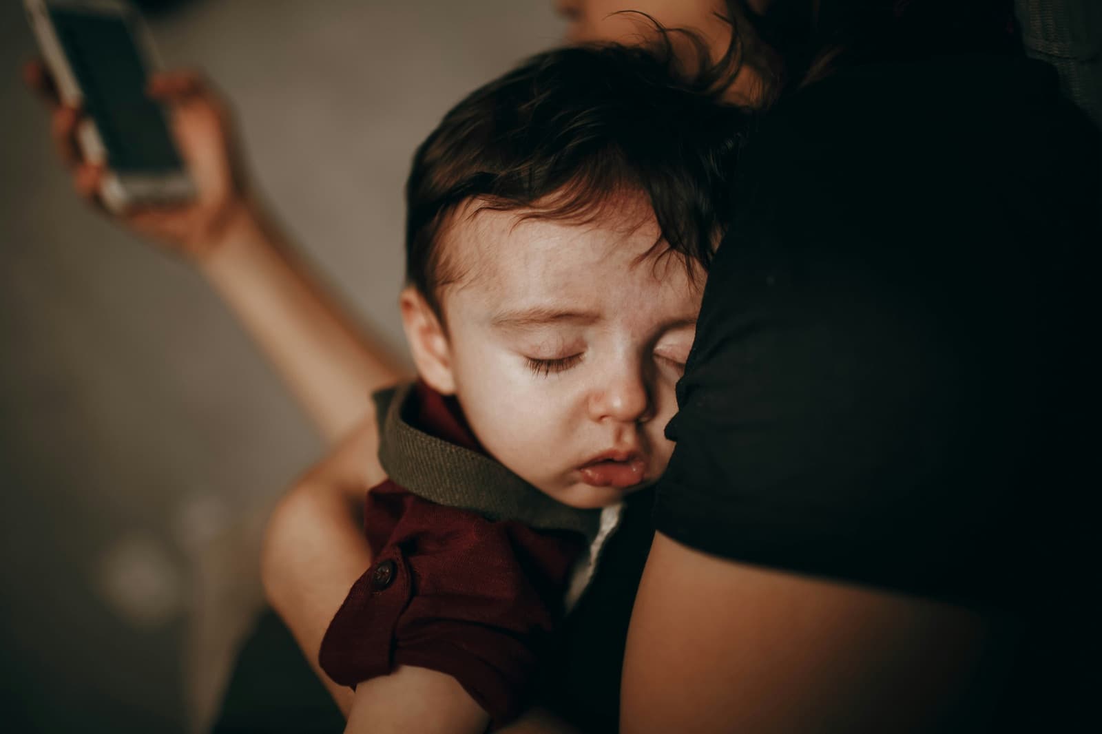A parent holding a sleeping toddler at the end of the day