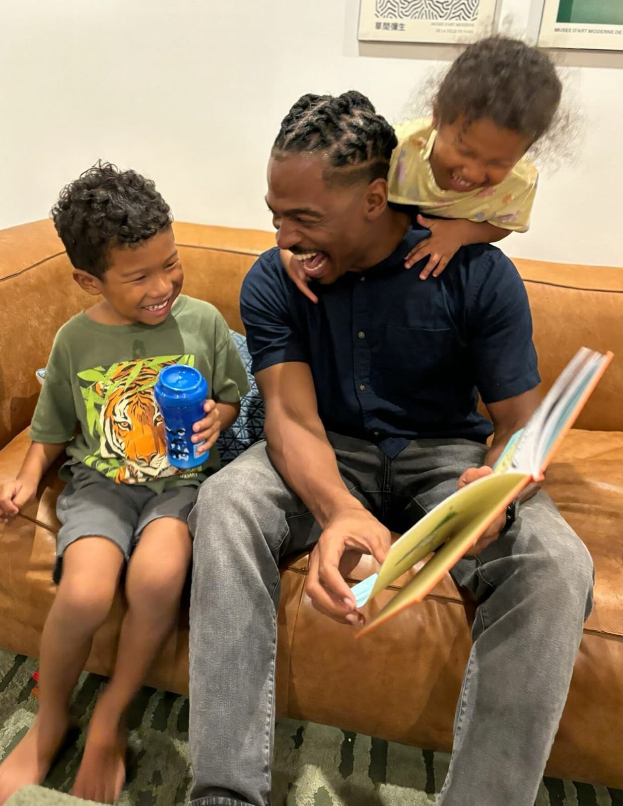 A dad laughing while reading a DWKD story with his two kids